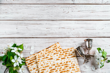 Happy Passover flatlay. Jewish matzo bread and wine glasses on white wooden background.