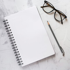 Blank, white notepad, glasses and pencil on the table
