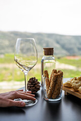 Glass of white wine, grissini breadsticks, and a water bottle on a table