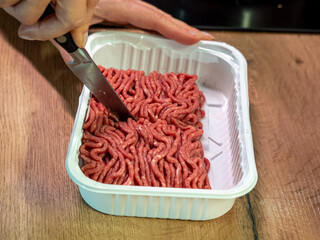 beef meat in white plastic packaging cut with a knife, top view
