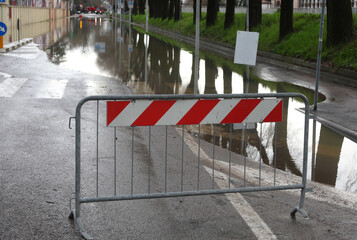 Road barrier to close the road to vehicle traffic because the road is completely flooded - 785641201