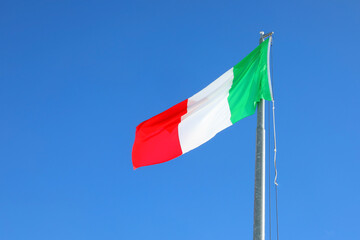 Large Italian flag with green, white, and red colors waving in the cloudless sky - 785641287