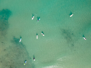 Aerial view by drone of people practicing Stand Up Paddle or SUP in Mediterranean turquoise clear sea.