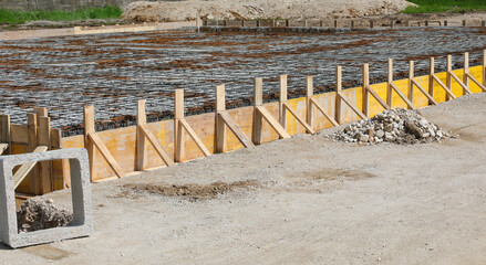 building formwork made with yellow wooden planks during laying cement to make the foundation of the...