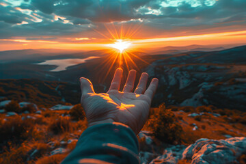 Hand Reaching Out to Sunset Horizon Over Mountains