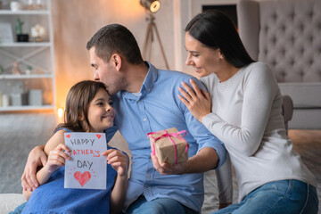 Happy father's day! Front view shot of happy family celebrating fathers day. Young man with a gift...
