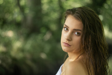 Portrait of a young brunette with wet hair looking at the camera. Horizontally. 