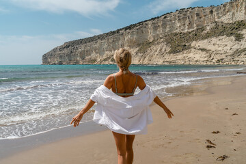 Happy woman in a white shirt stands with open arms, enjoying her holiday on the beach © blackday
