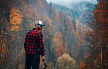 Handsome Lumberjack in Red Checkered Shirt with Axe in Autumn Foggy Forest - 785650892