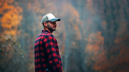 Handsome Lumberjack in Red Checkered Shirt with Axe in Autumn Foggy Forest - 785651021