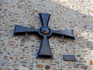 Cruz negra templaria en la fachada de una iglesia antigua de piedra, en verano de 2021 en la ciudad de León, España