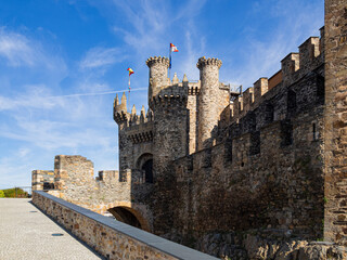 Vista de la muralla y las torres en la entrada del Castillo de los templarios de Ponferrada, fortaleza medieval con muralla de piedra y banderas en León, España, verano de 2021