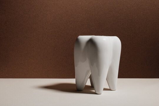 Minimalistic white tooth model against brown backdrop