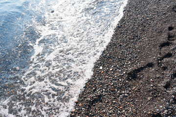 Detail of cobblestones in the transparent water of the famous Vlychada Beach, Santorini. Background, natural stone, texture.