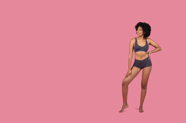 Fototapeta na wymiar Standing African American lady in sportswear on pink background