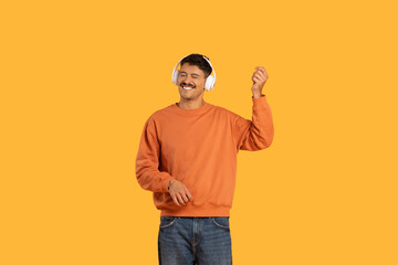 Man dancing with headphones on yellow background