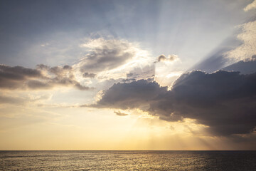 Naklejka na ściany i meble Sunbeams Breaking Through Clouds Over Sea