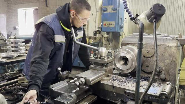 Young apprentice mastering the lathe machine in industrial workshop