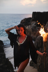 Mysterious woman on the beach at dusk and holding a flaming torch
