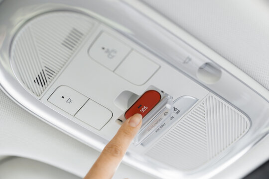 Finger pressing emergency sos button to contact with call center to ask for help after car accident. SOS button in a car as a symbol for the eCall system in European cars