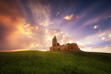 ruins of the church of San Jorde de Ojeda, Palencia under a spectacular sky at sunset after the...