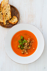 Squash soup with bread crumbs, parsley served with crusty bread on white wood, high angle view - 785667018