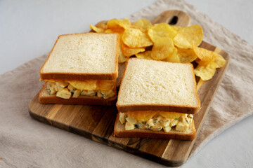 Fototapeta na wymiar Homemade Egg Salad Sandwich with Potato Chips on a wooden board, side view.