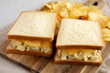 Homemade Egg Salad Sandwich with Potato Chips on a wooden board, side view. - 785667834