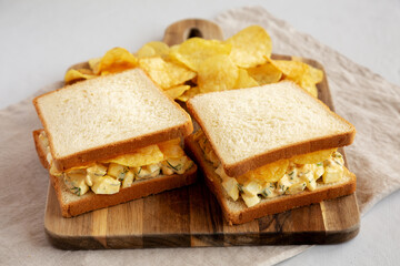 Homemade Egg Salad Sandwich with Potato Chips on a wooden board, side view. - 785668006