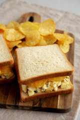 Homemade Egg Salad Sandwich with Potato Chips on a wooden board, side view. - 785668087