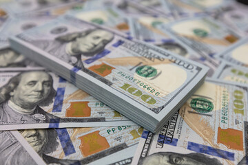 Obraz na płótnie Canvas Pile of US 100 dollar banknotes on dollars background