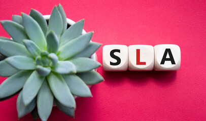 SLA - Service Level Agreement. Wooden cubes with word SLA. Beautiful red background with succulent...