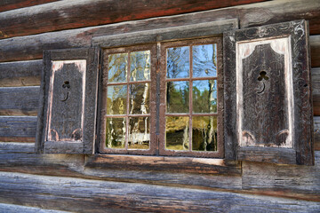 A beautiful, rustic, vintage window with open blinds of an old, traditional Norwegian wooden house
