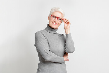 Elderly lady adjusting glasses with a smile