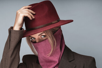 Portrait of a woman with stylish maroon hat and wild rag covering her face