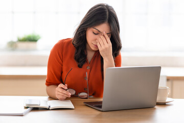 Woman working on laptop at wooden desk