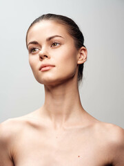 Sensual portrait of young woman with bare shoulders gazing up at camera in natural light