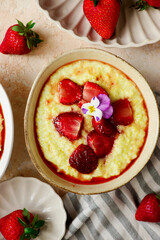 Creamy millet porridge with baked strawberries in to the bowl