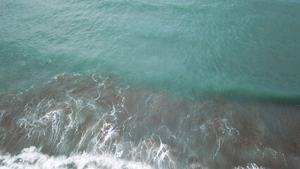 aerial view of ocean waves hitting the beach
