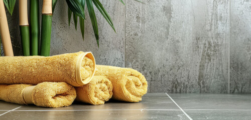 Soft yellow towels rolled up against a textured grey stone wall.