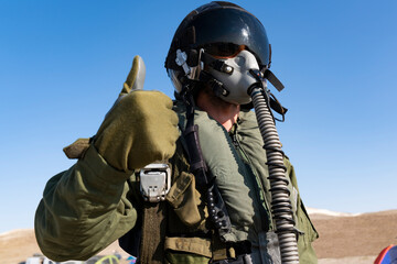 A man in a military, in pilot suit uniform is giving a thumbs up sign. He is wearing a pilot mask © FATIR29