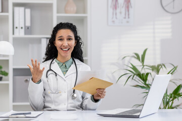 Cheerful female doctor, with curly hair, Discussing medical reports with a smile in a well-lit...