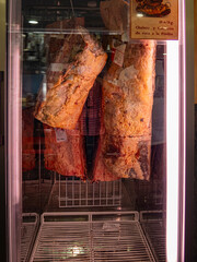 Carne de ternera de máxima calidad colgada en un escaparate con luces rojizas, dentro de una nevera en un restaurante de Galicia, España 2021 - obrazy, fototapety, plakaty
