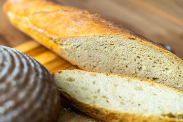 A slice of freshly baked baguette cut on a wooden cutting board. Selected Focus