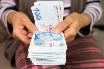 Closeup of wrinkled hands holding turkish lira banknotes  