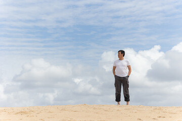 A man stands on a beach looking out at the ocean