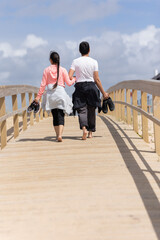 Two people walking on a wooden bridge
