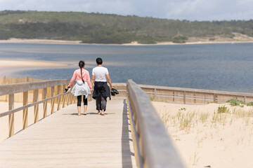 A couple walking on a wooden boardwalk by the water
