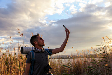 backpacker man taking selfie in nature. A man is taking a selfie with his cell phone in a nature
