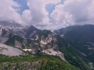 Aerial panorama of marble quarries Carrara Italy. Marble quarry top view. Aerial panorama on the Carrara marble quarry. Famous marble quarry in the mountains of Italy. Cumulus clouds over mountains.